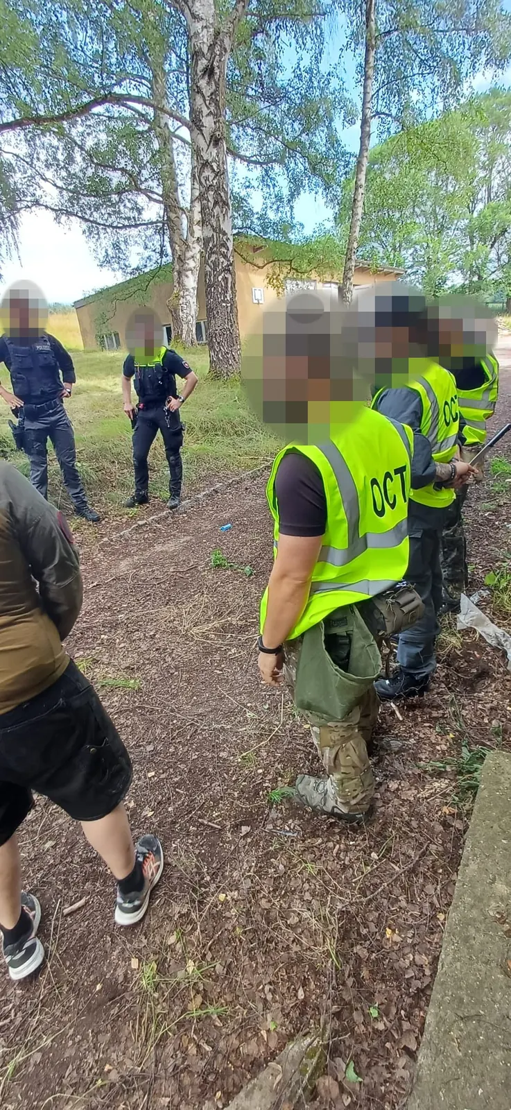 Trainer und Teilnehmende bei einer Übungsbesprechung im Gelände